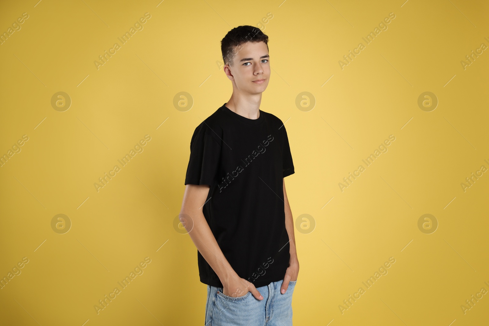 Photo of Teenage boy wearing black t-shirt on yellow background