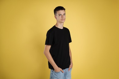 Teenage boy wearing black t-shirt on yellow background