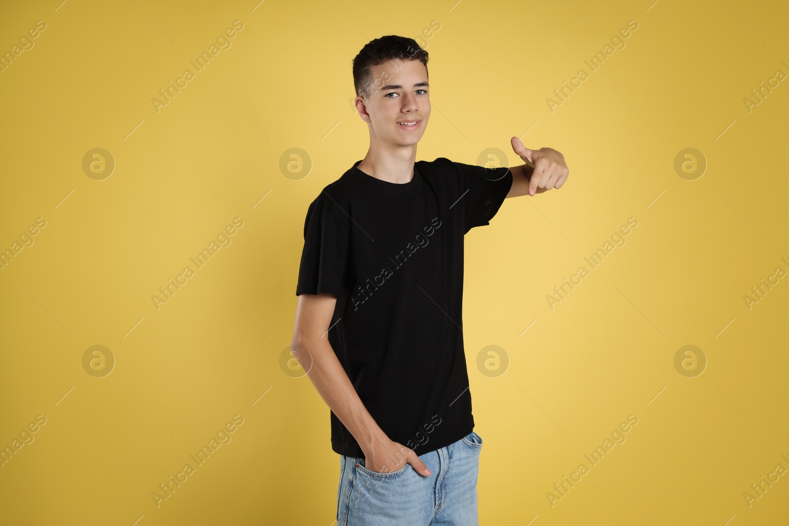 Photo of Teenage boy wearing black t-shirt on yellow background