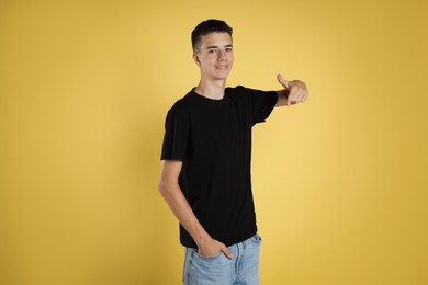 Teenage boy wearing black t-shirt on yellow background