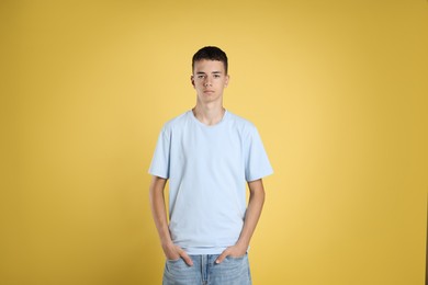 Photo of Teenage boy wearing light blue t-shirt on yellow background