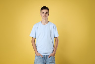 Teenage boy wearing light blue t-shirt on yellow background