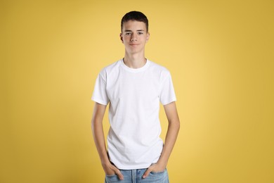 Teenage boy wearing white t-shirt on yellow background