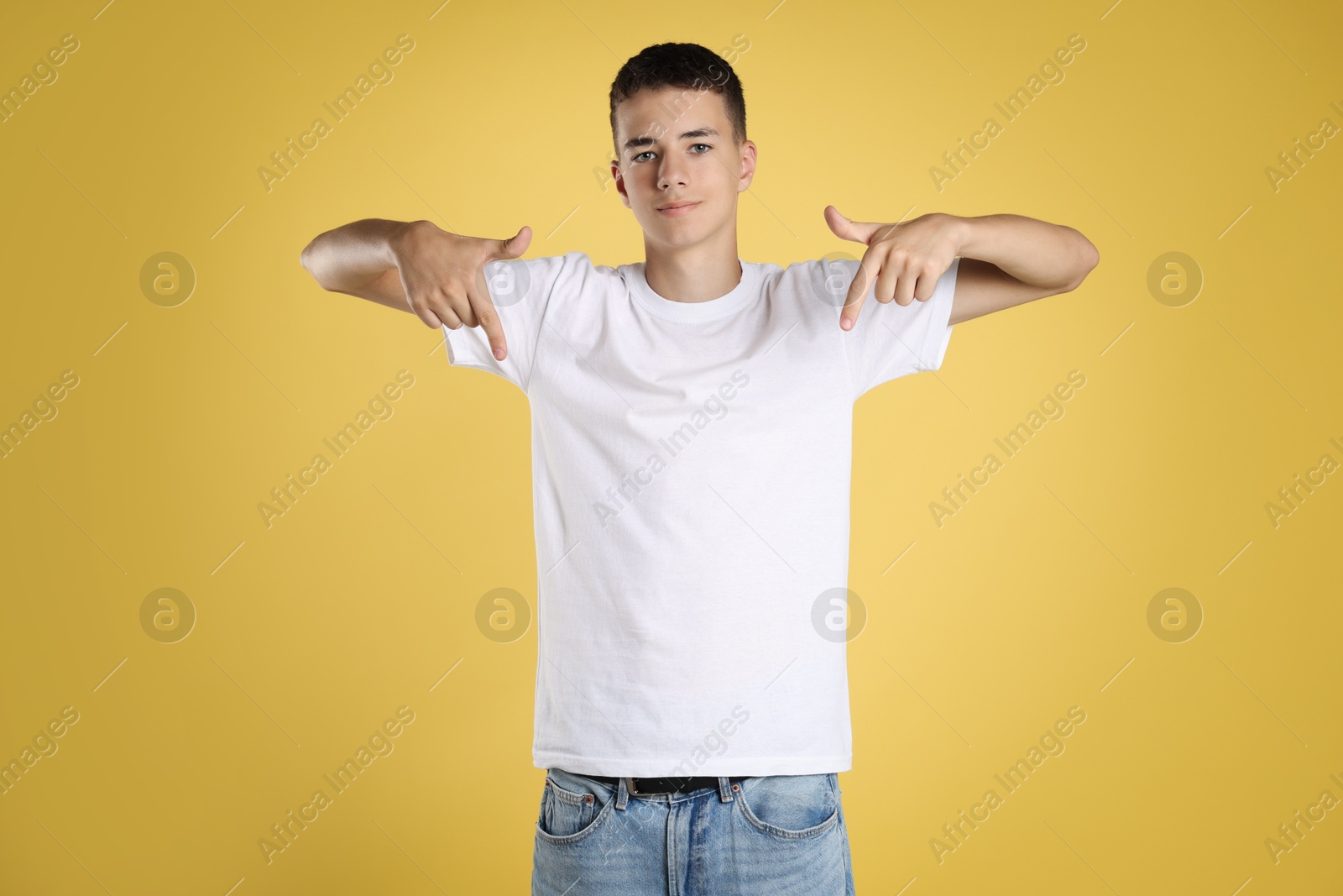 Photo of Teenage boy wearing white t-shirt on yellow background