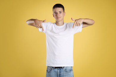 Teenage boy wearing white t-shirt on yellow background