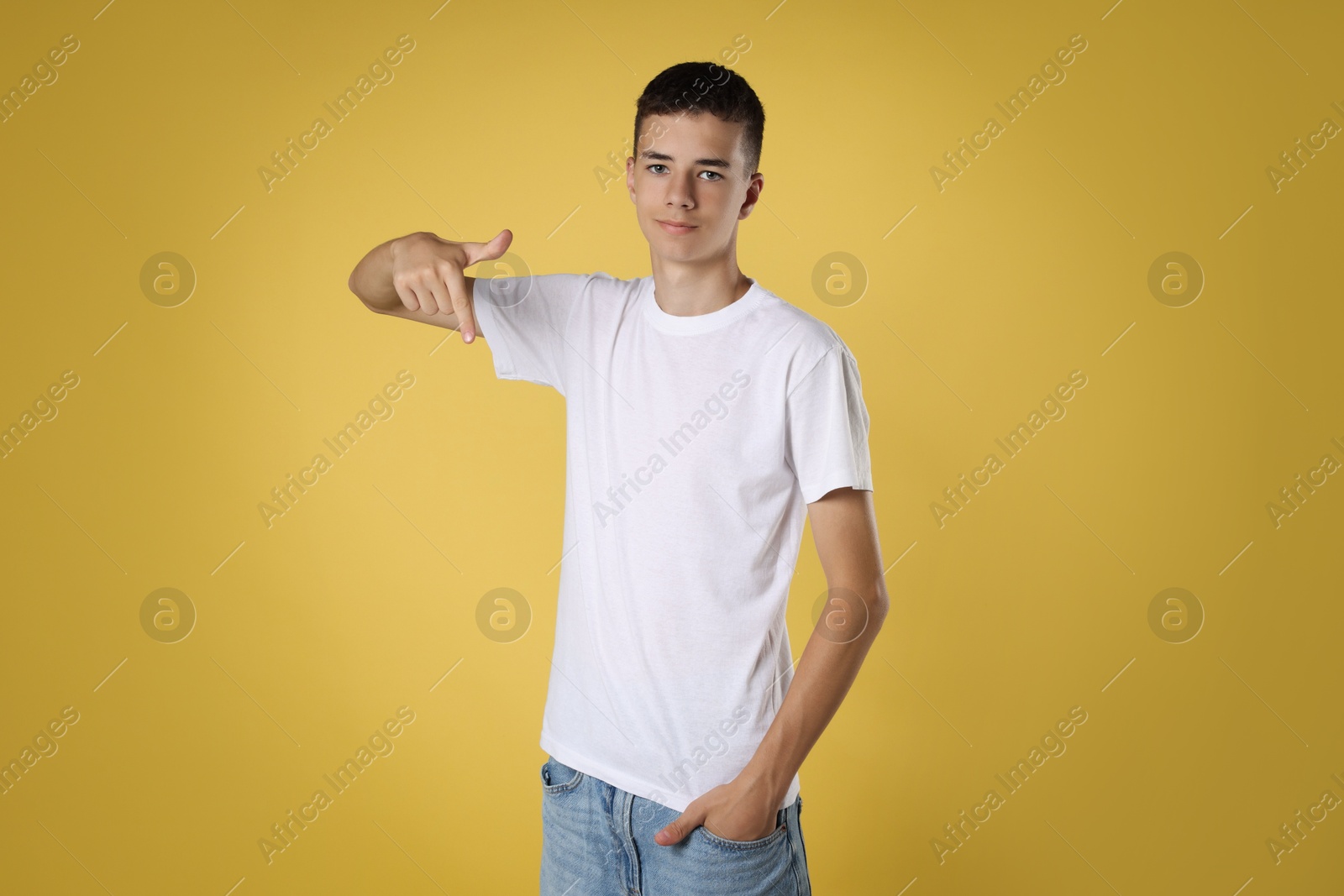 Photo of Teenage boy wearing white t-shirt on yellow background