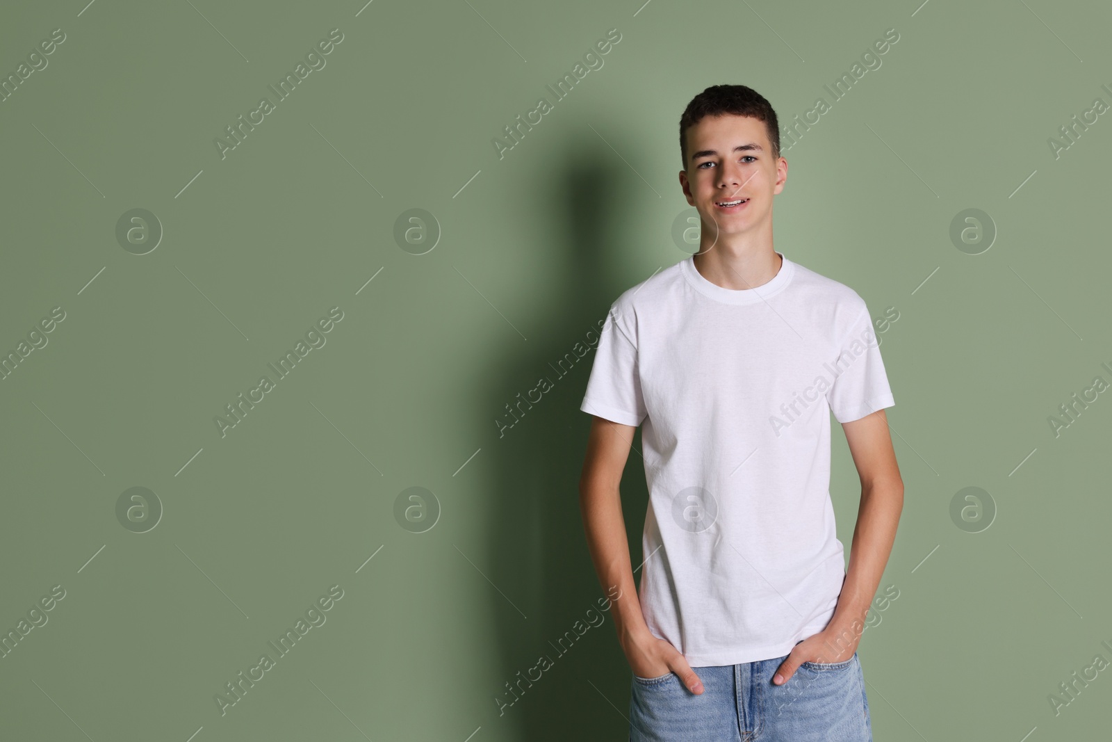 Photo of Teenage boy wearing white t-shirt on green background, space for text