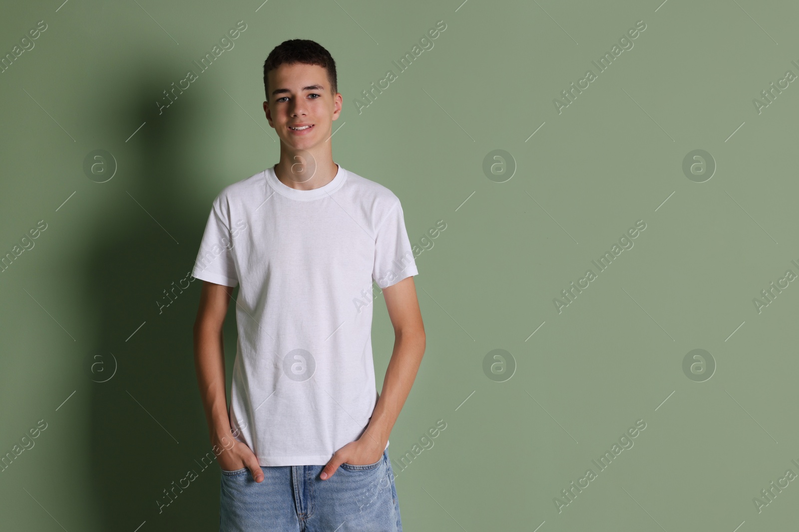 Photo of Teenage boy wearing white t-shirt on green background, space for text