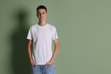 Photo of Teenage boy wearing white t-shirt on green background, space for text