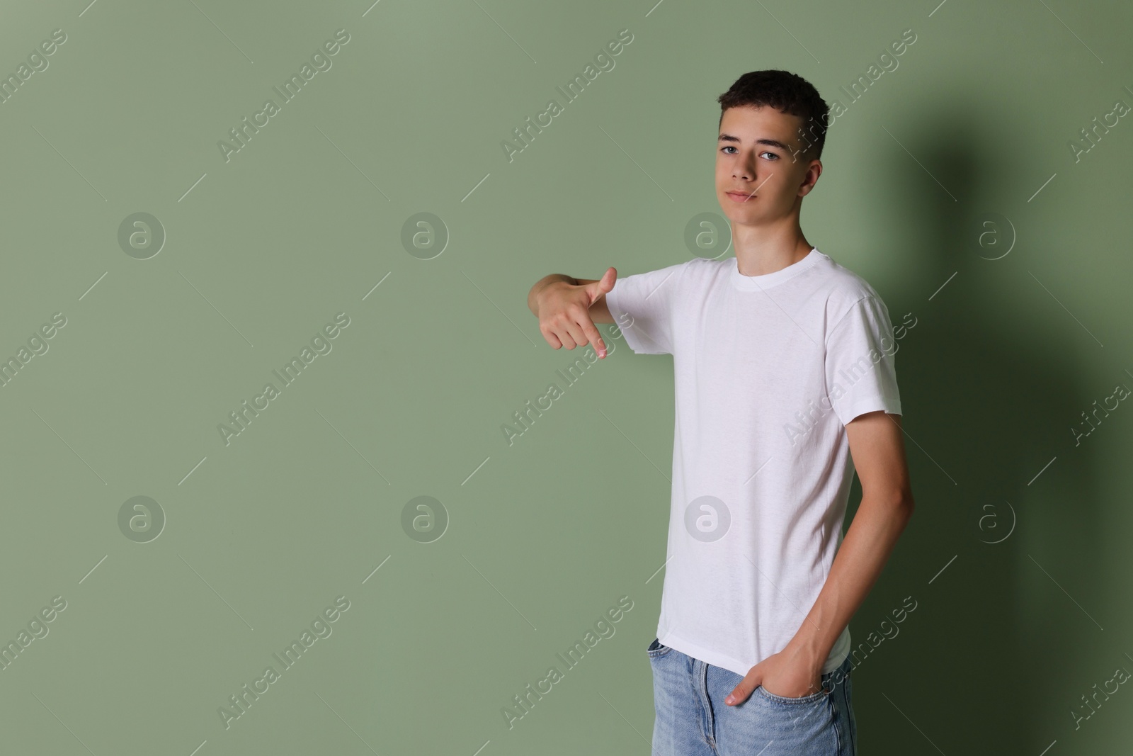 Photo of Teenage boy wearing white t-shirt on green background, space for text