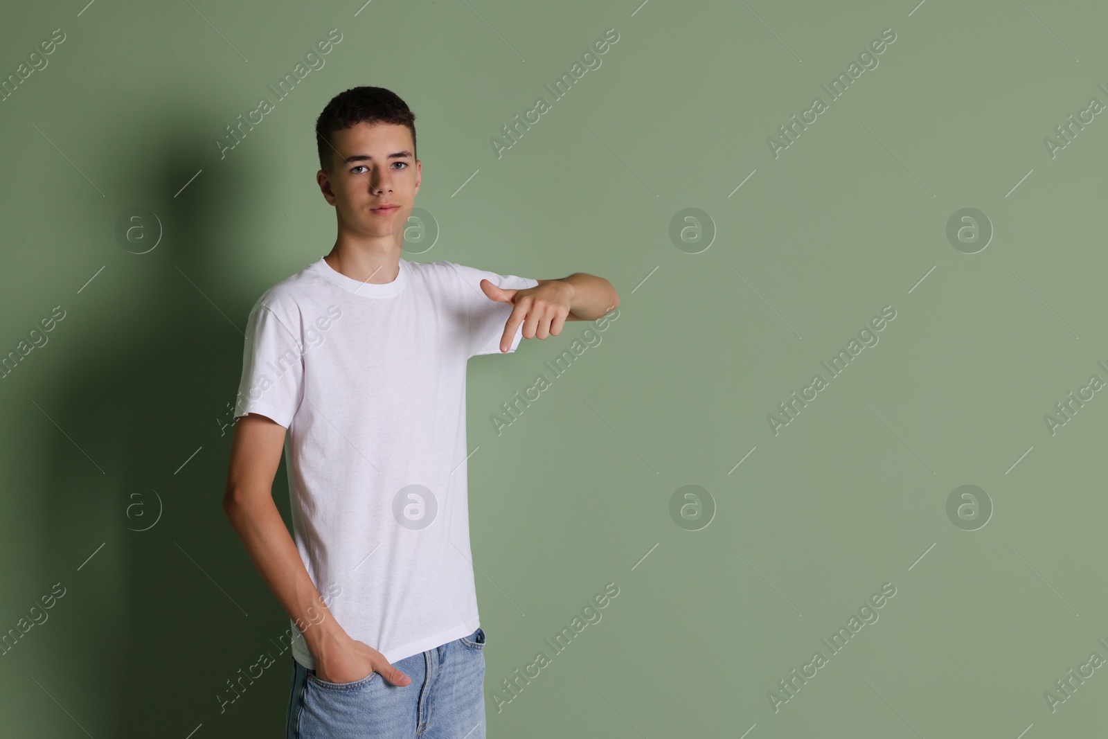 Photo of Teenage boy wearing white t-shirt on green background, space for text