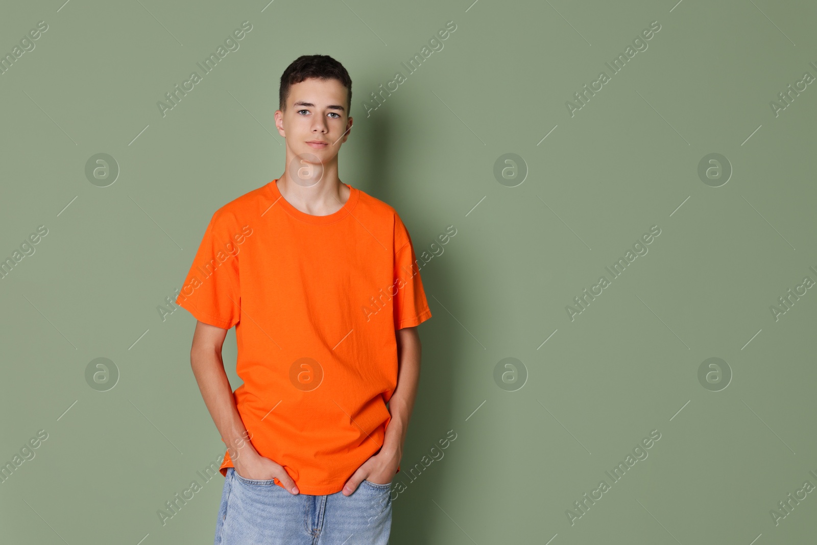 Photo of Teenage boy wearing orange t-shirt on green background, space for text