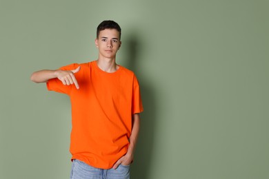 Photo of Teenage boy wearing orange t-shirt on green background, space for text