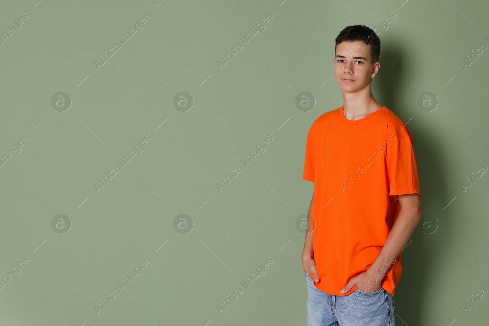 Photo of Teenage boy wearing orange t-shirt on green background, space for text