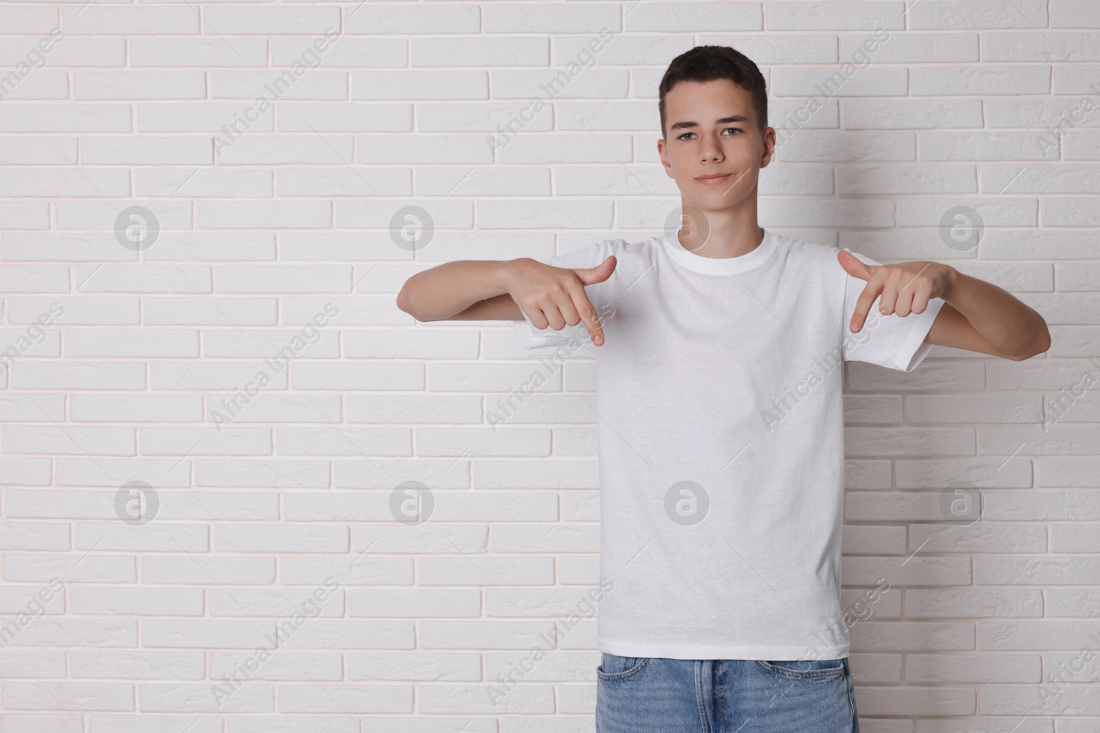 Photo of Teenage boy wearing t-shirt near white brick wall, space for text