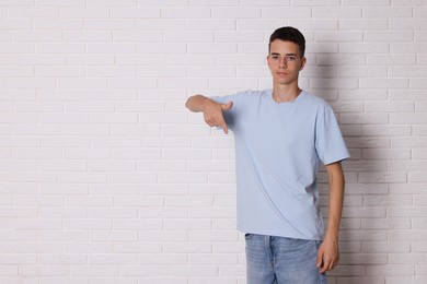 Photo of Teenage boy wearing light blue t-shirt near white brick wall, space for text