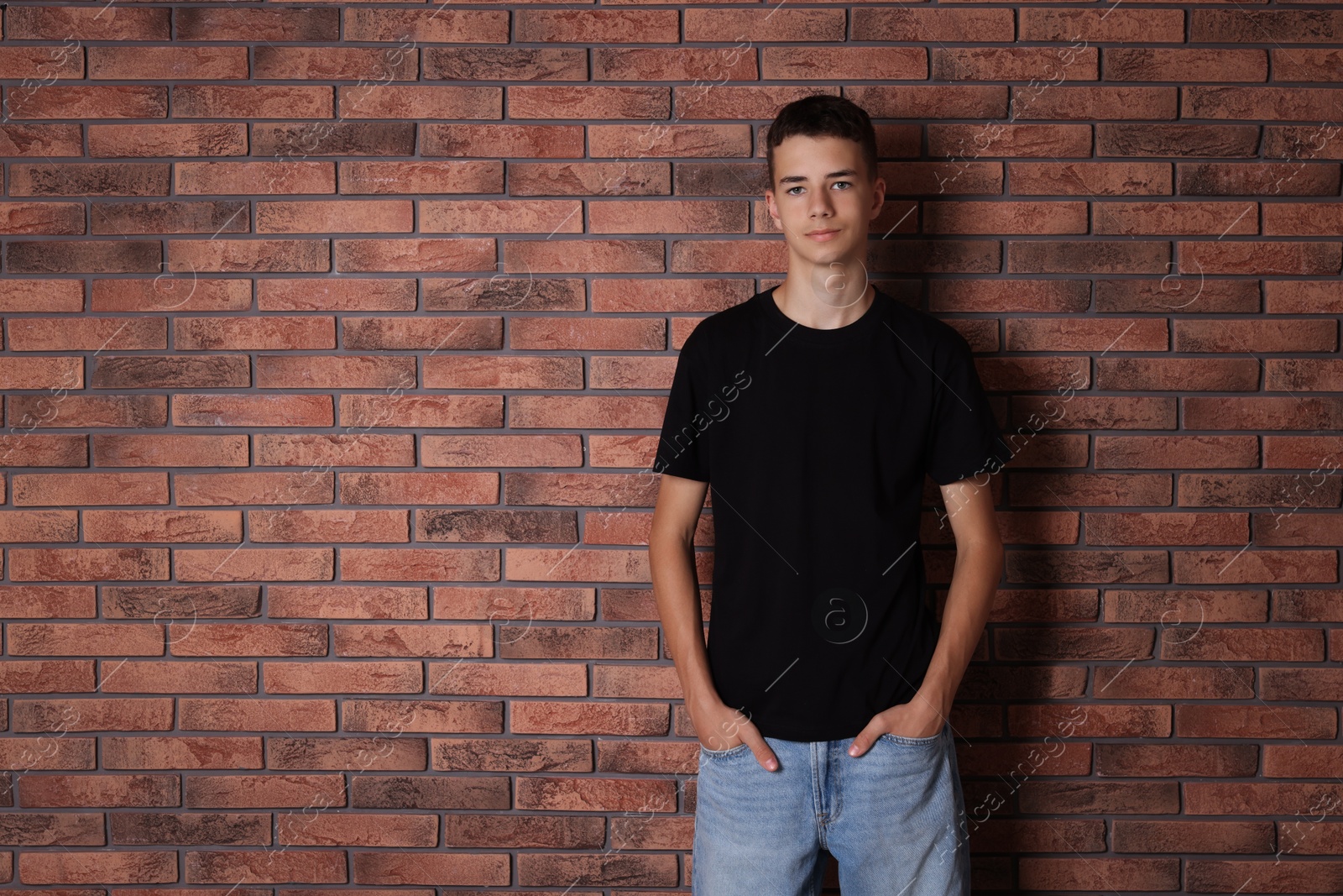 Photo of Teenage boy wearing black t-shirt near brick wall, space for text