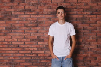 Photo of Teenage boy wearing white t-shirt near brick wall, space for text