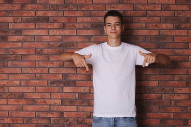 Photo of Teenage boy wearing white t-shirt near brick wall, space for text