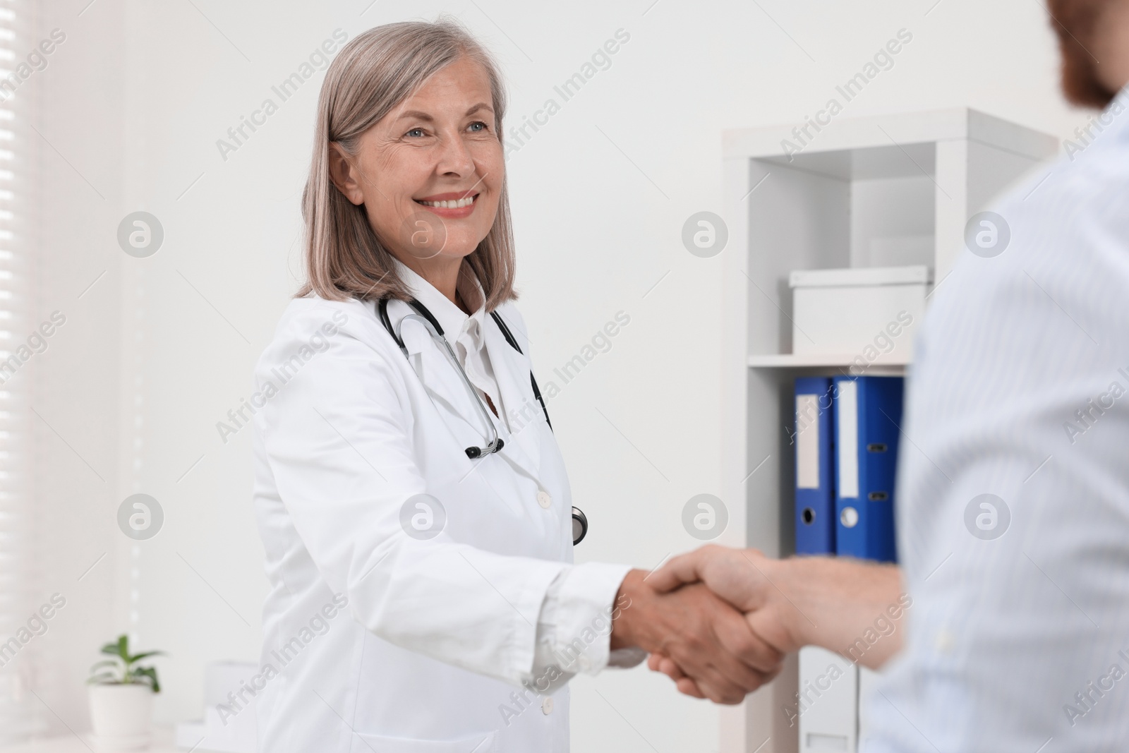 Photo of Senior doctor shaking hands with patient in hospital