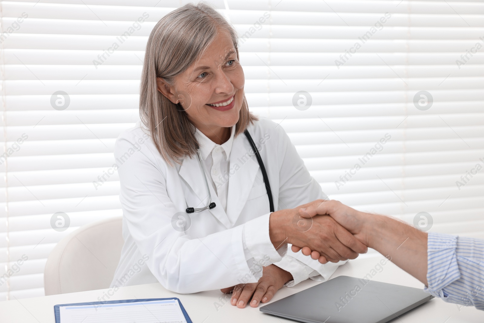 Photo of Senior doctor shaking hands with patient in hospital