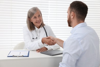 Photo of Senior doctor shaking hands with patient in hospital