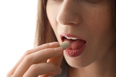 Woman taking pill on light background, closeup