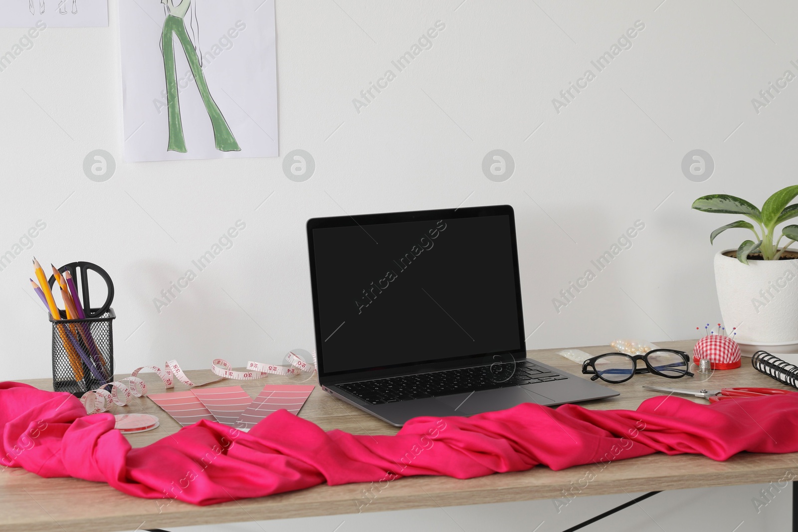 Photo of Laptop and different designer`s supplies on wooden table in workshop