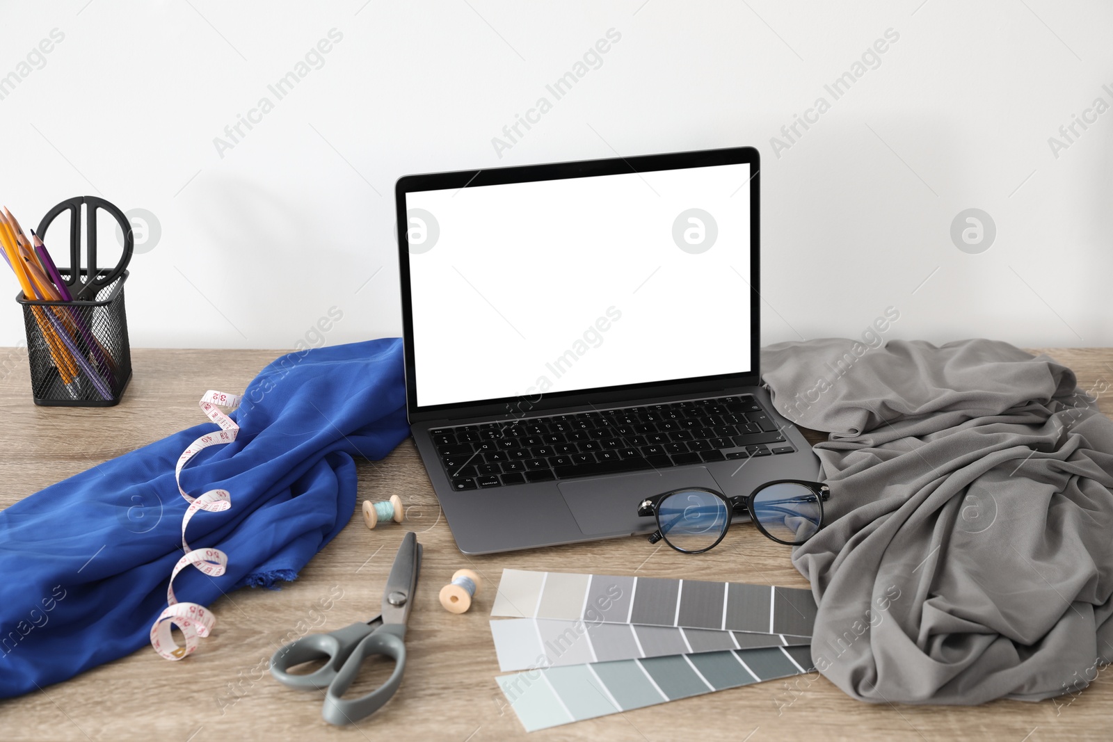 Photo of Laptop and different designer`s supplies on wooden table in workshop