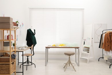 Photo of Fashion designer`s workplace with fashionable clothes, fabric samples and sewing supplies