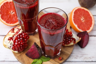 Photo of Fresh beetroot smoothie in glasses, grapefruit, beet and pomegranate on white wooden table. Vegan drink