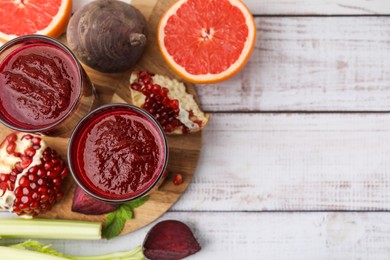 Photo of Fresh beetroot smoothie in glasses, grapefruit, beet and pomegranate on white wooden table, flat lay. Space for text