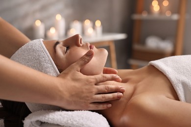 Photo of Attractive woman enjoying face massage in spa salon, closeup