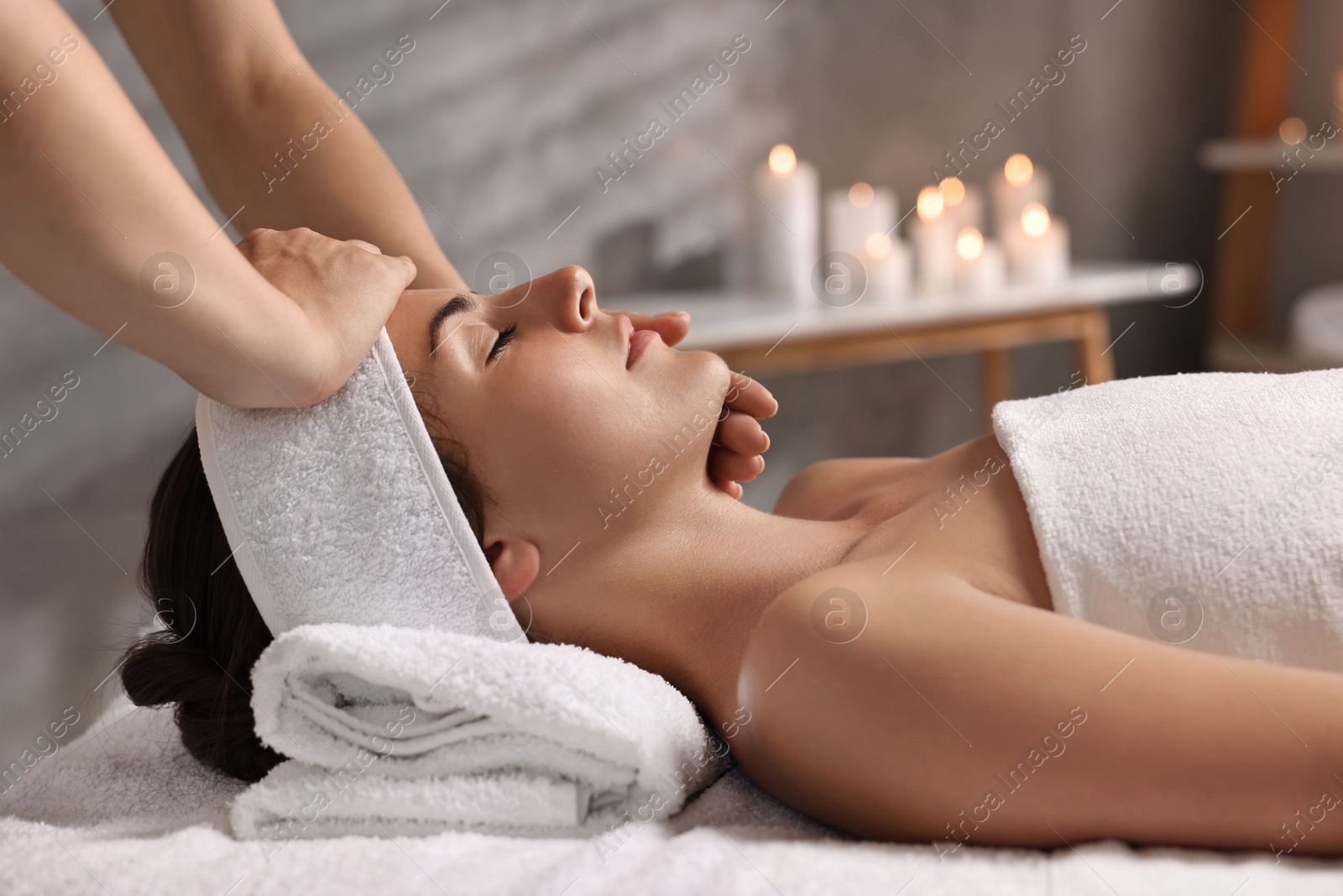 Photo of Attractive woman enjoying face massage in spa salon, closeup