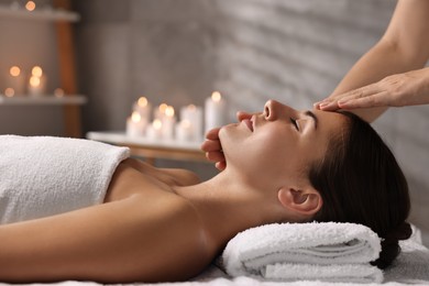 Photo of Attractive woman enjoying face massage in spa salon, closeup