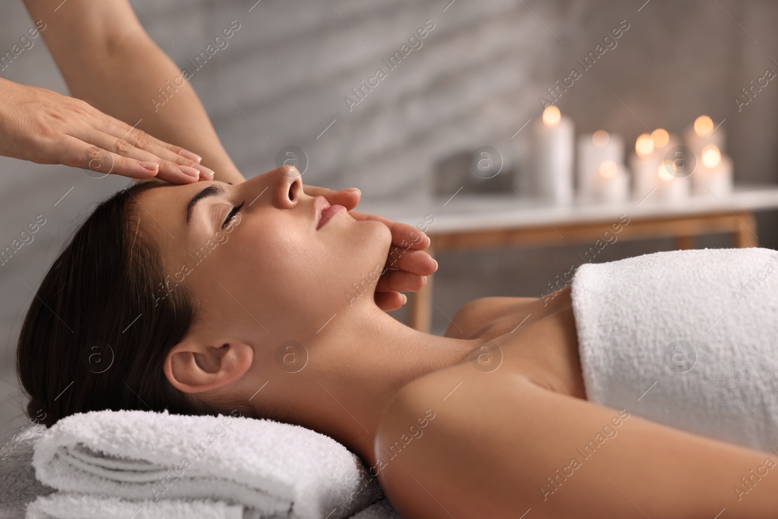 Photo of Attractive woman enjoying face massage in spa salon, closeup