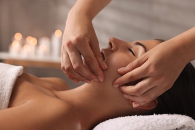 Photo of Attractive woman enjoying face massage in spa salon, closeup