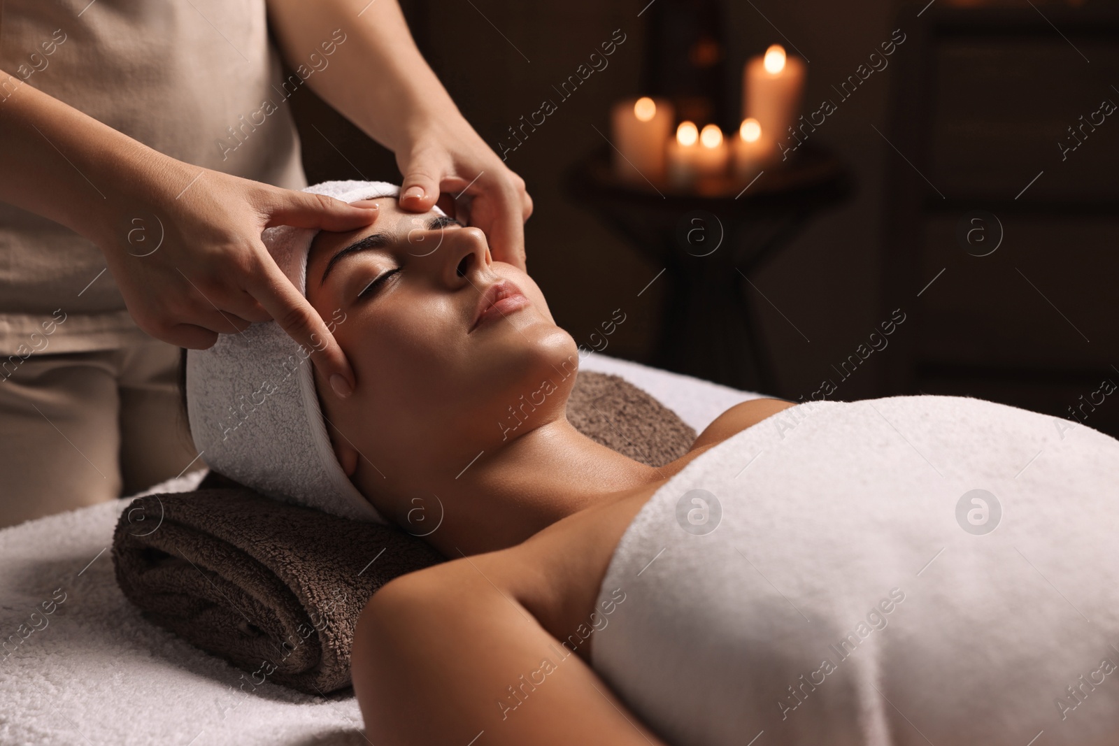 Photo of Attractive woman enjoying face massage in spa salon, closeup