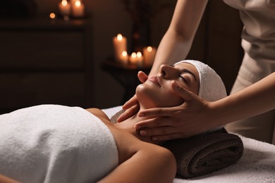 Photo of Attractive woman enjoying face massage in spa salon, closeup