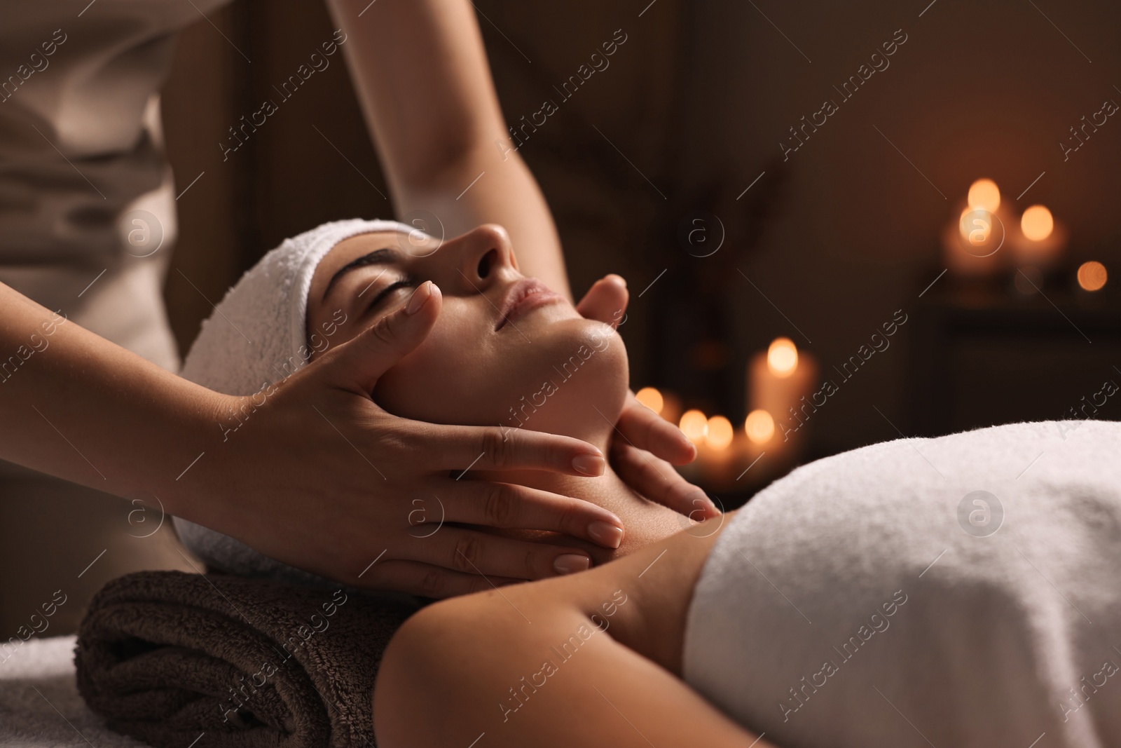 Photo of Attractive woman enjoying face massage in spa salon, closeup