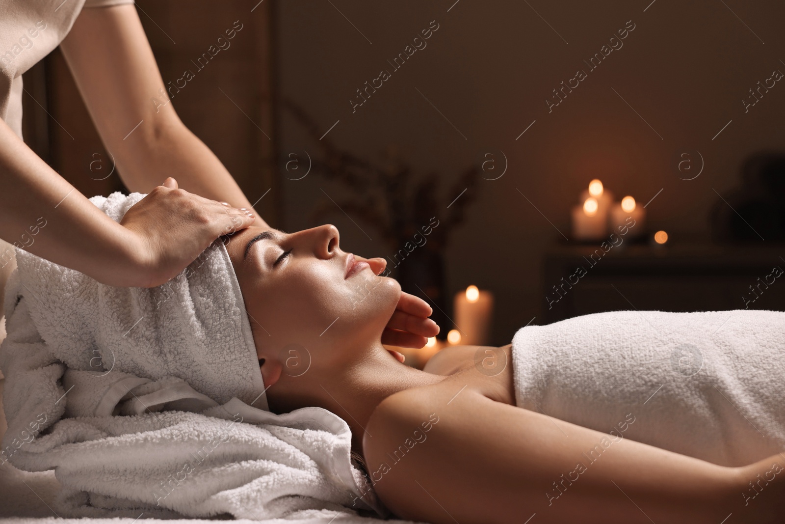 Photo of Attractive woman enjoying face massage in spa salon, closeup