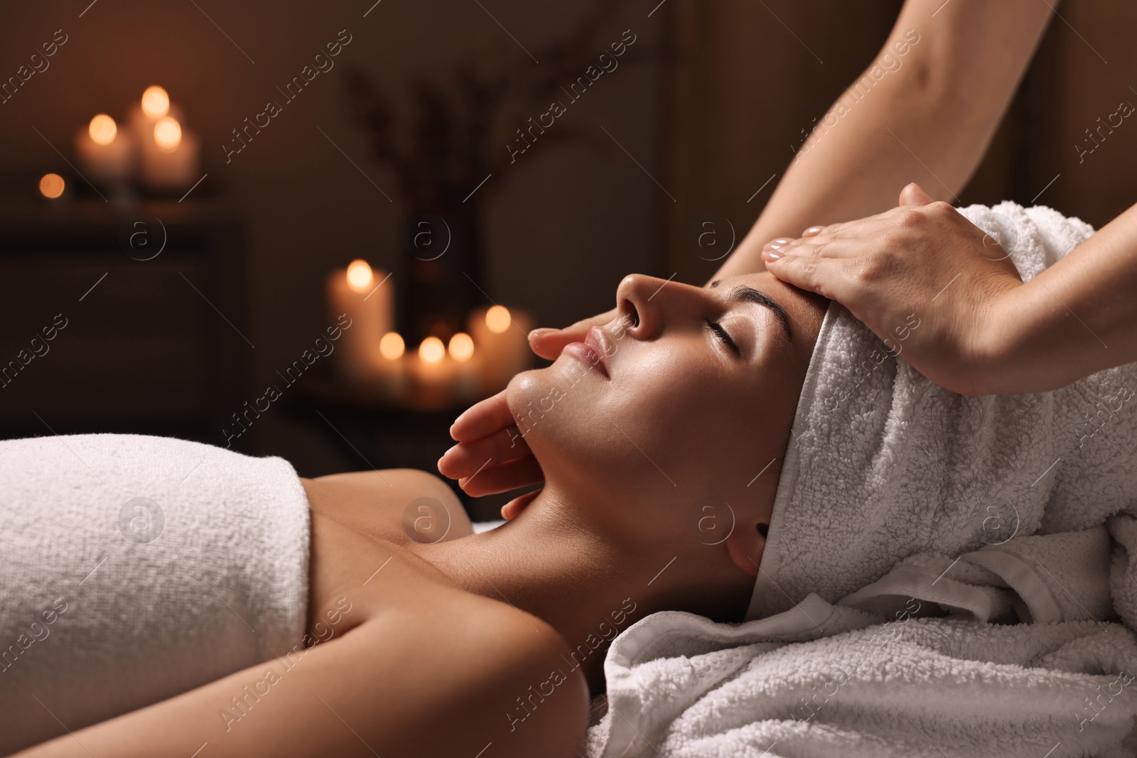 Photo of Attractive woman enjoying face massage in spa salon, closeup