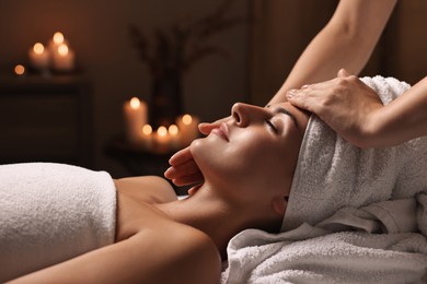 Attractive woman enjoying face massage in spa salon, closeup