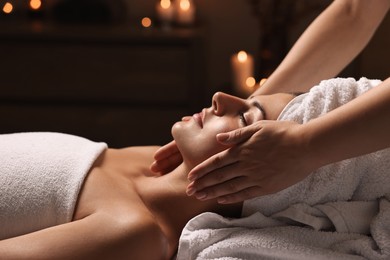 Photo of Attractive woman enjoying face massage in spa salon, closeup