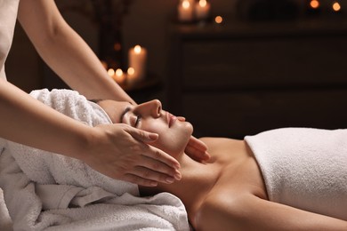 Attractive woman enjoying face massage in spa salon, closeup