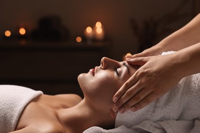 Photo of Attractive woman enjoying face massage in spa salon, closeup