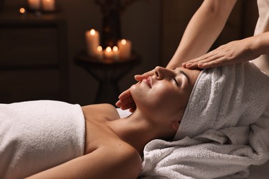 Photo of Attractive woman enjoying face massage in spa salon, closeup