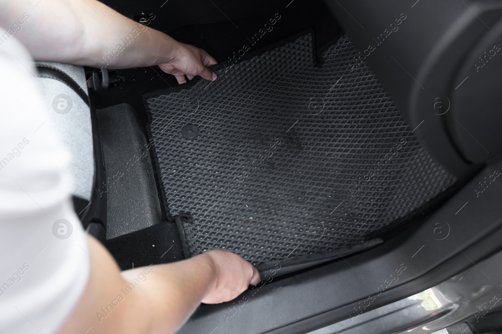 Photo of Man taking grey rubber car mat from auto, closeup