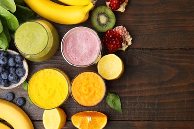 Photo of Tasty smoothies in glasses and ingredients on wooden table, flat lay. Space for text