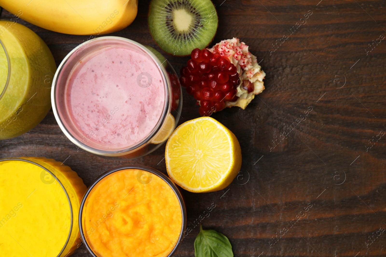 Photo of Tasty smoothies in glasses and ingredients on wooden table, flat lay. Space for text